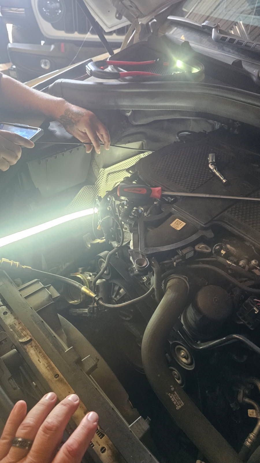 Mechanic in blue coveralls filling out a checklist beside an open car engine