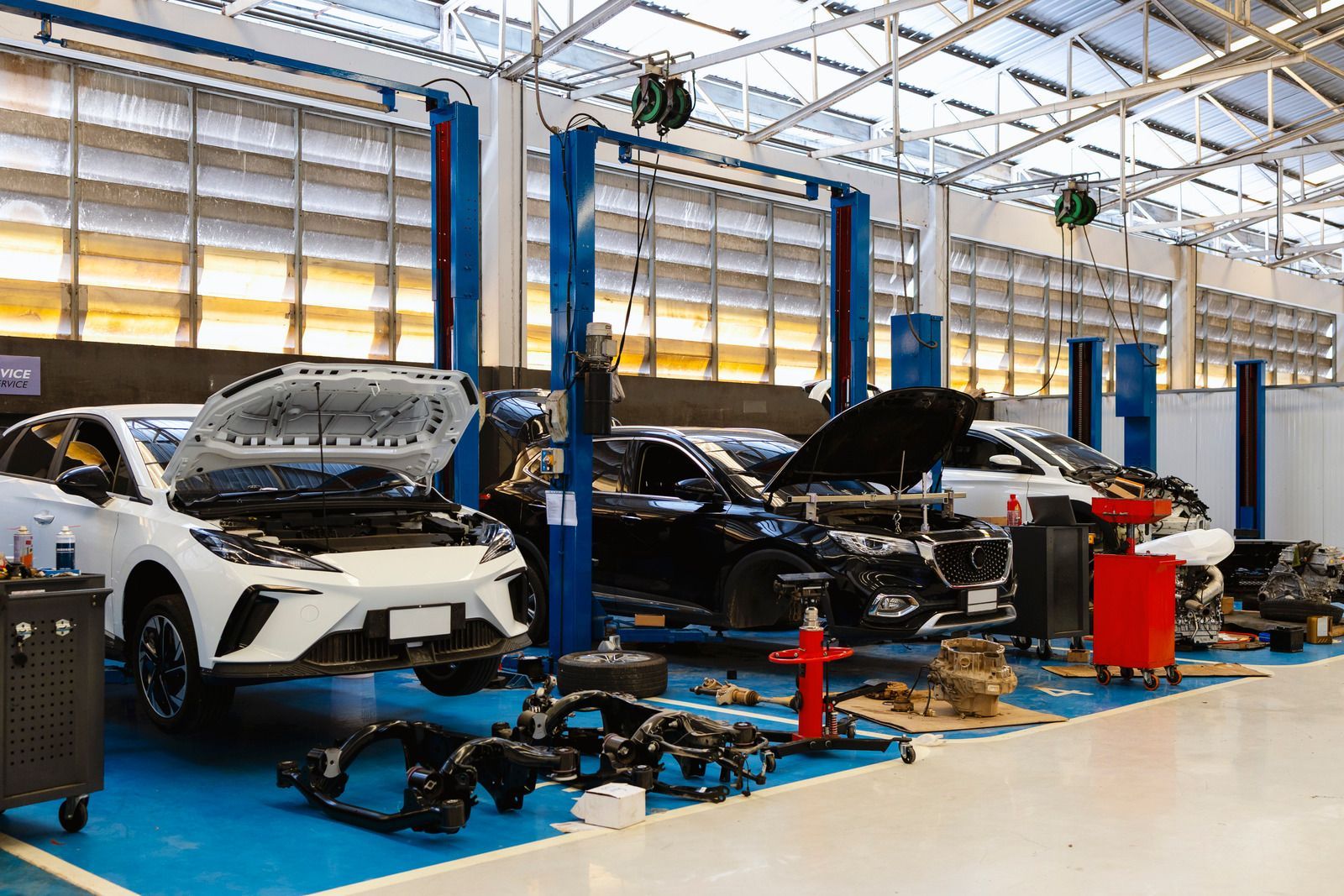 Auto repair shop with cars lifted on blue hoists and tools scattered on the floor