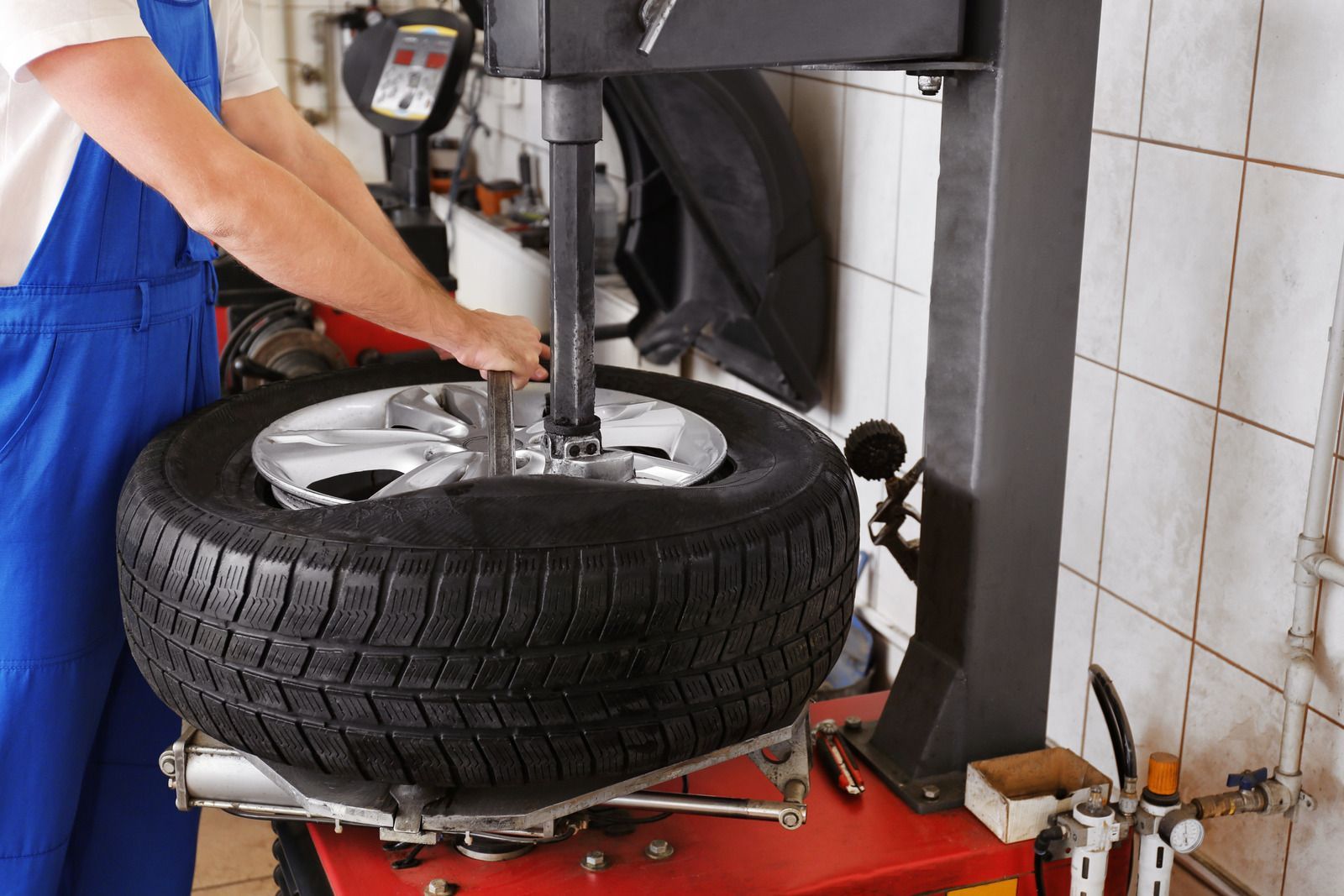 Mechanic using a tire-changing machine on a car tire in a garage