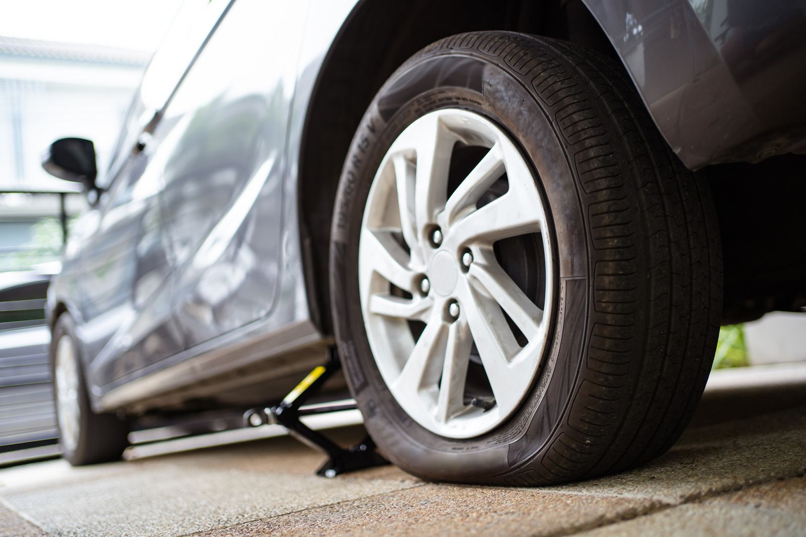 Car with flat tire on a roadside, lifted by a jack