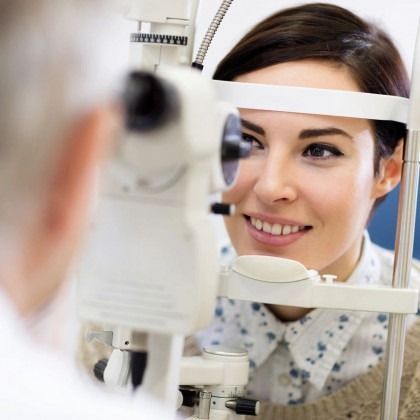 Woman smiling during an eye exam with an optometrist device in the foreground
