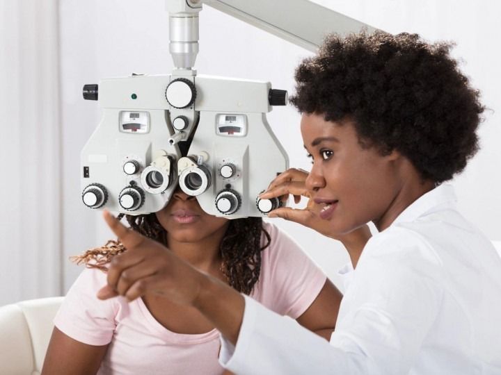Eye exam with an optometrist and a patient using a phoropter in a clinic