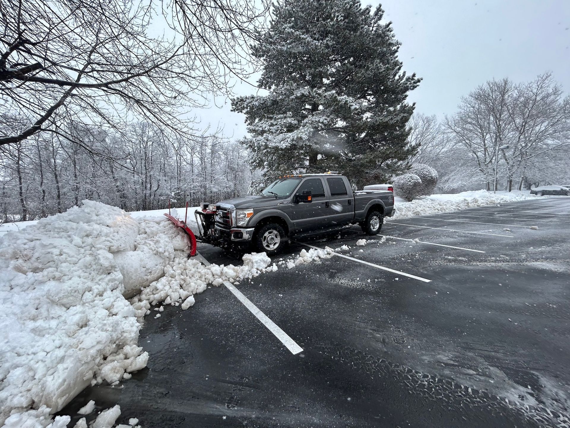 A truck is plowing snow in a parking lot.