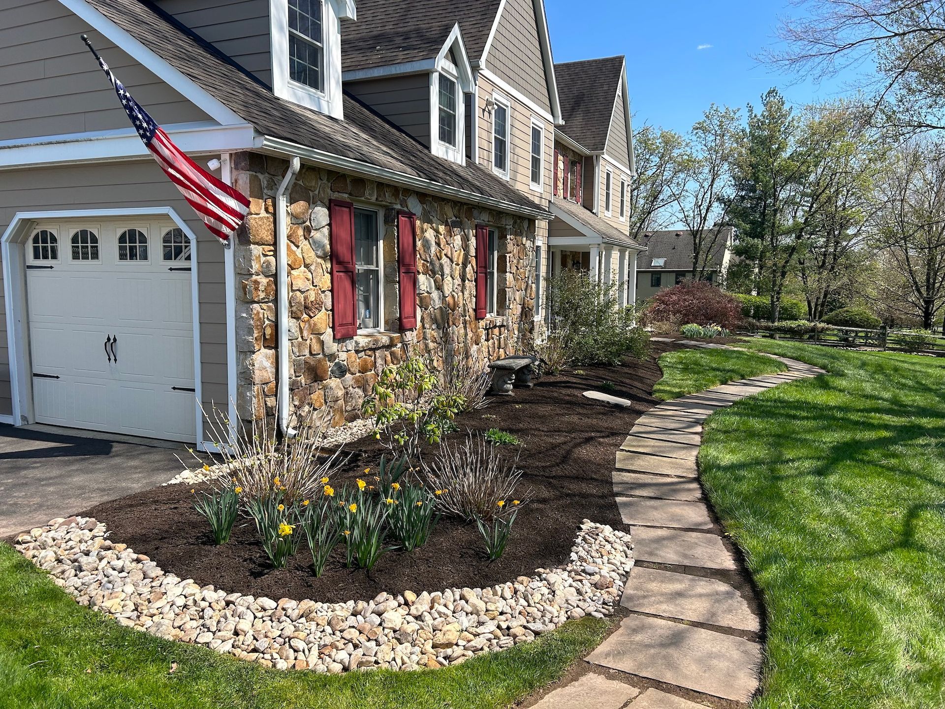A house with a stone facade and a walkway leading to it.