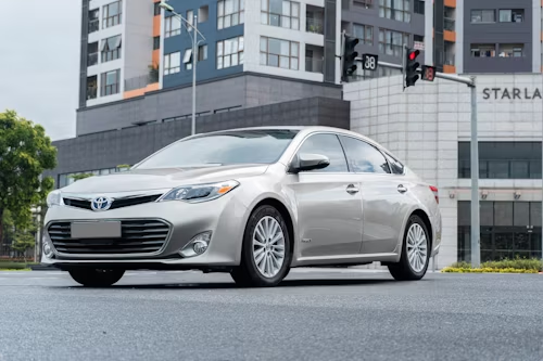 Silver Toyota Avalon sedan parked on a city street, with a modern building in the background.