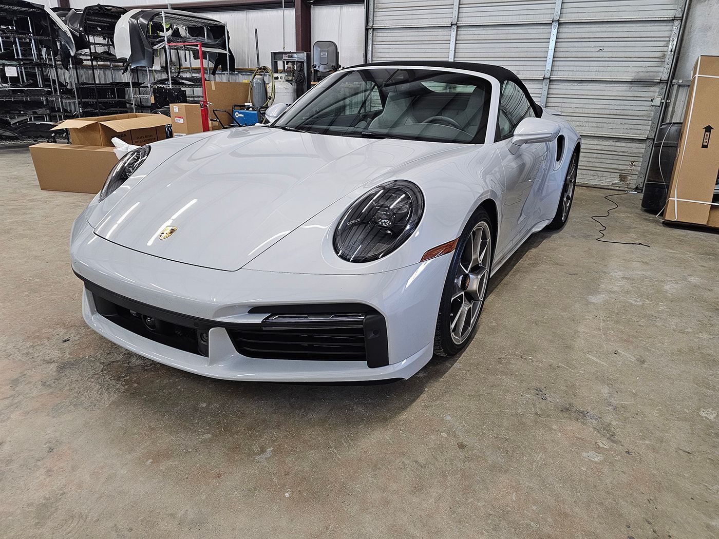 White Porsche sports car parked in a garage or warehouse, front-left view.