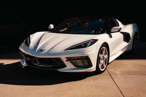 White sports car parked in sunlight.