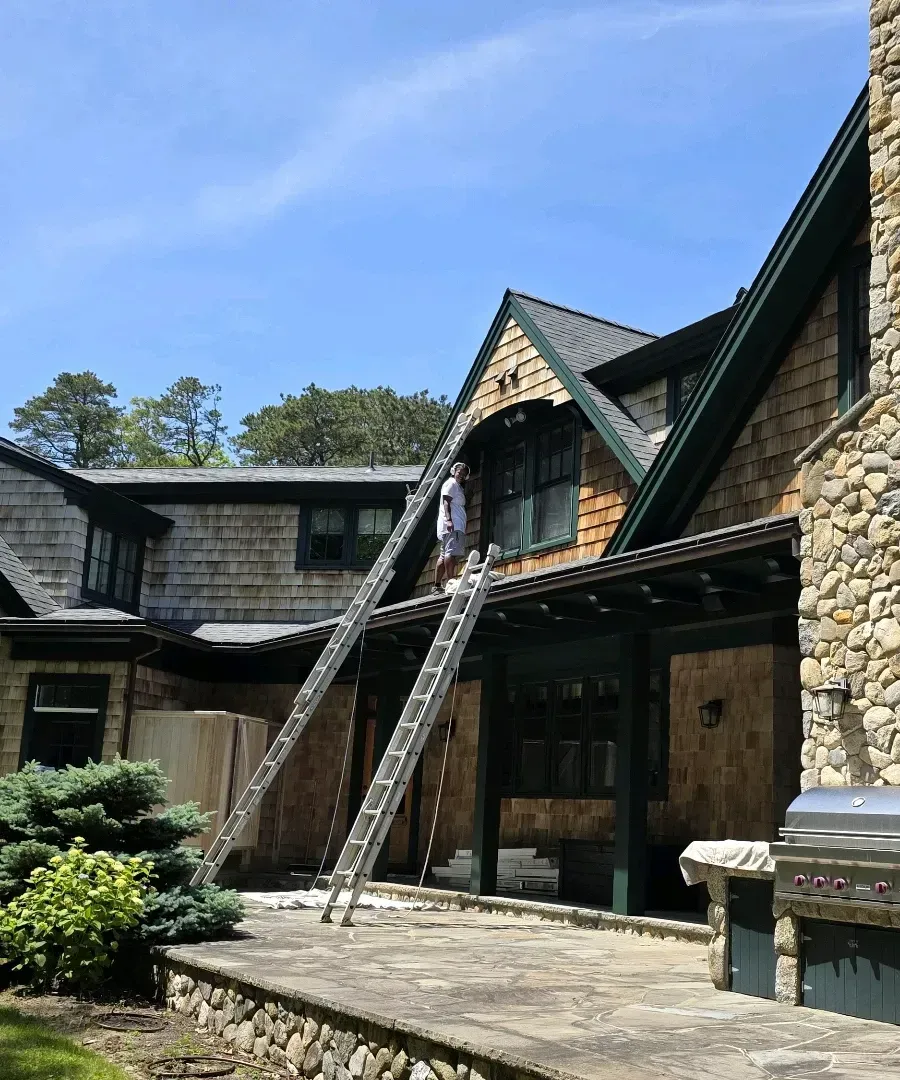 Stone lodge courtyard with steep gabled roofs and wooden ladders against the facade under a blue sky