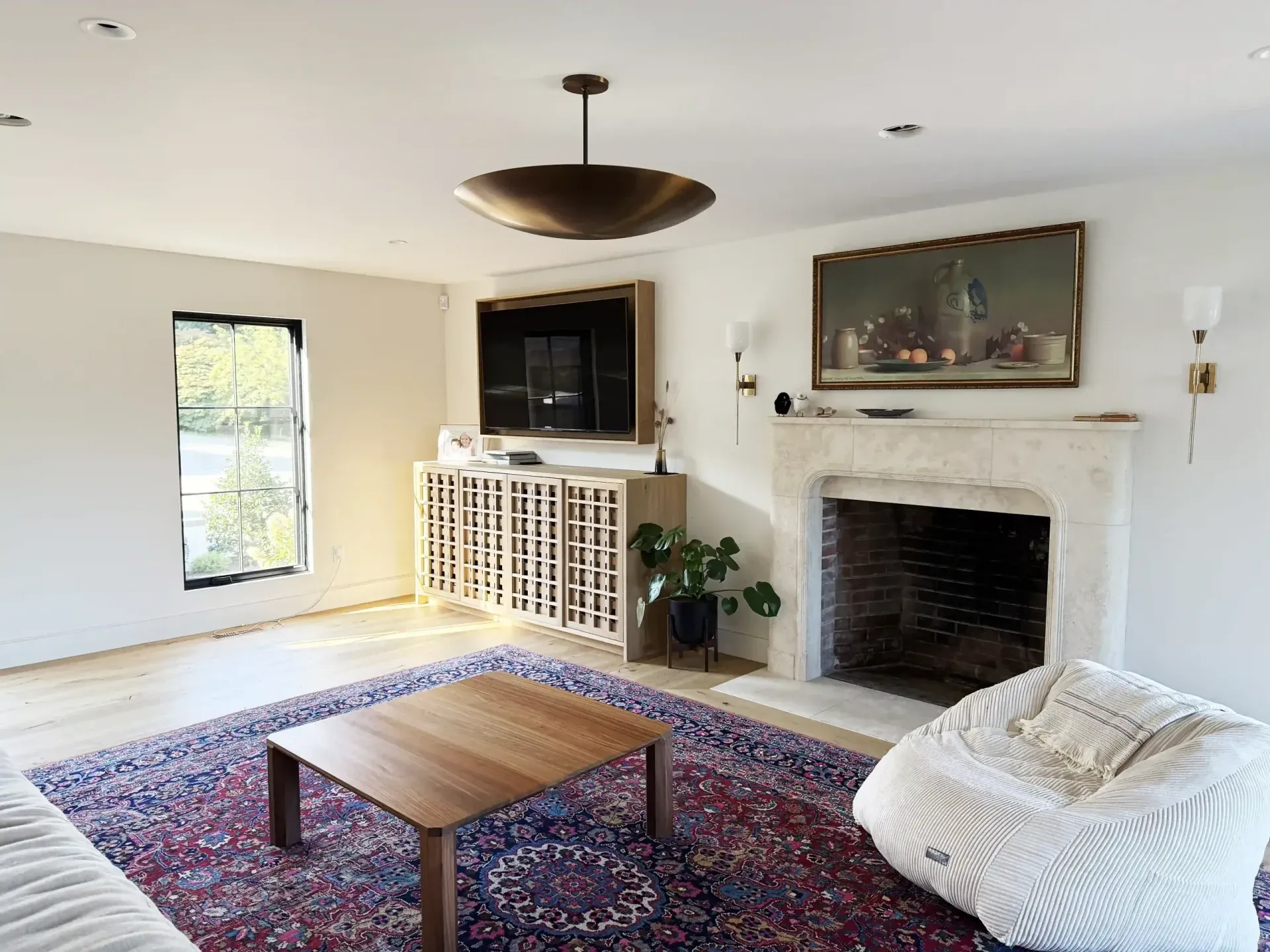 Bright living room with fireplace, TV, patterned rug, coffee table, and white beanbag chair.
