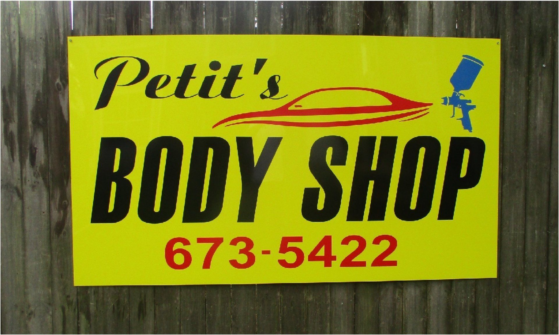 Yellow sign for Petit's Body Shop with black text, a car graphic, spray gun, and phone number.
