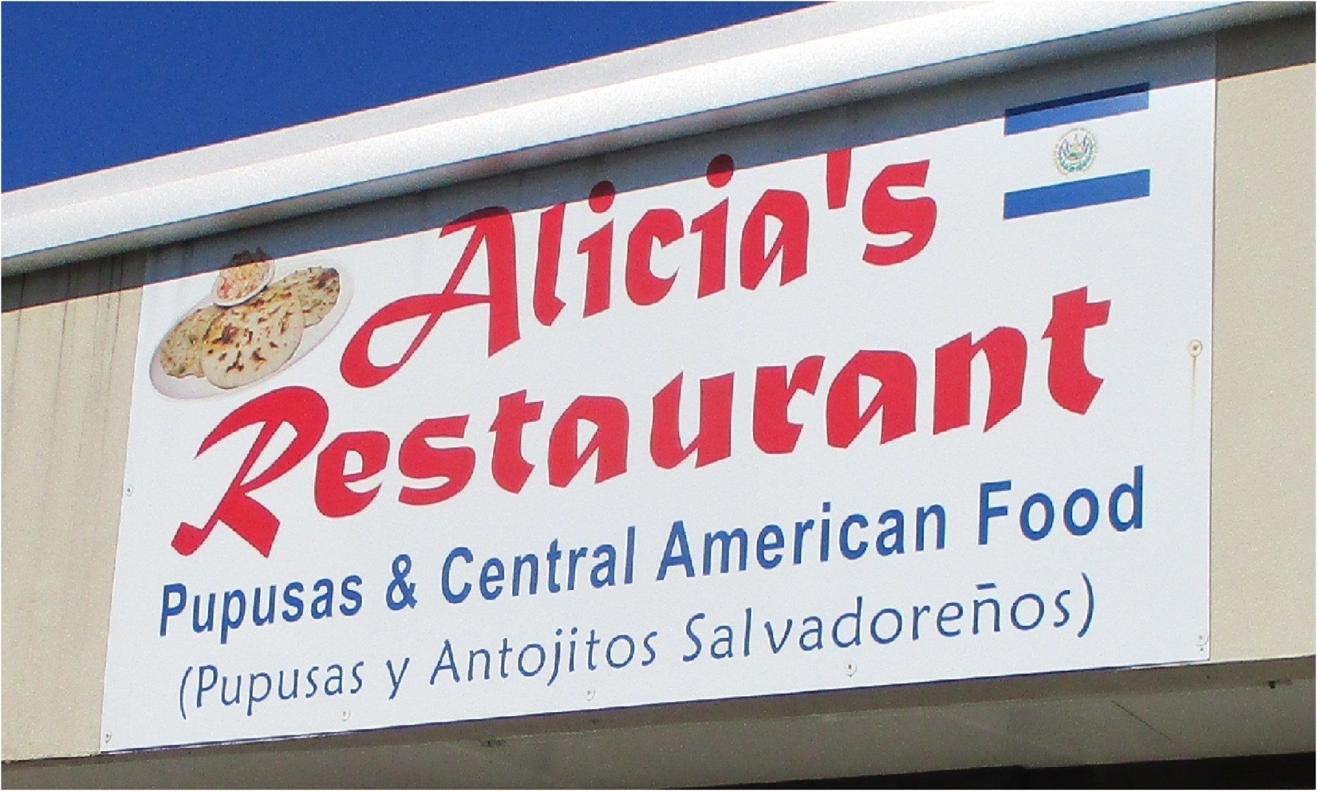 Sign for Alicia's Restaurant featuring red lettering on a white background, showcasing pupusas and Central American food, with the flag of El Salvador.