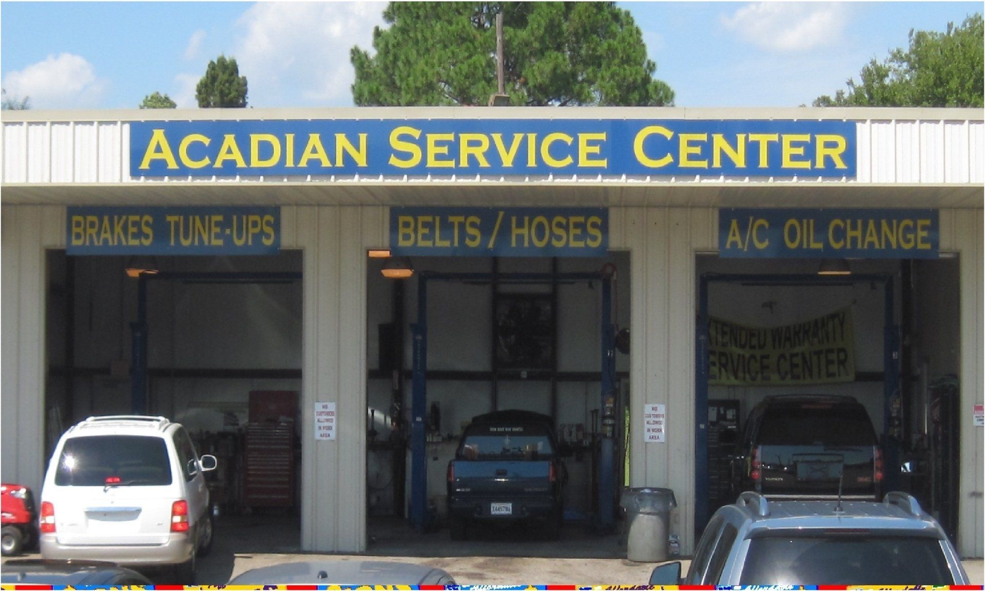 Acadiana Service Center storefront with bays for auto repair services. Signage for brakes, tune-ups, belts, hoses, A/C, and oil changes.