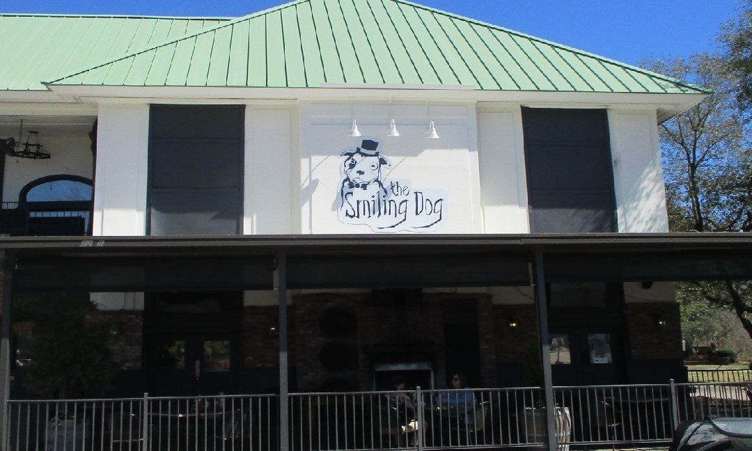 A two-story building with a black awning and green roof. The sign says