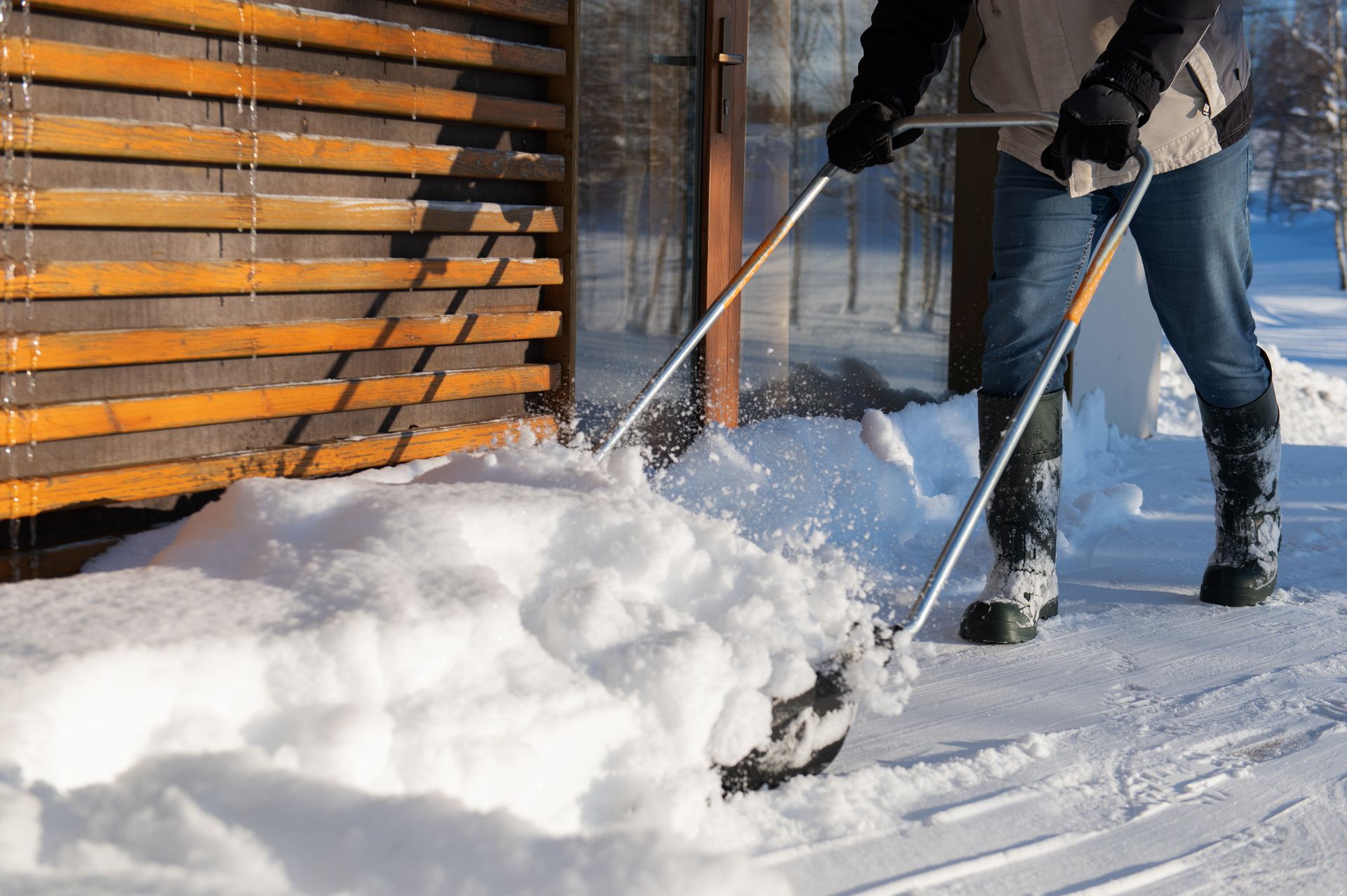 Eine Person schaufelt mit einer Schneefräse Schnee von einem Gehweg.