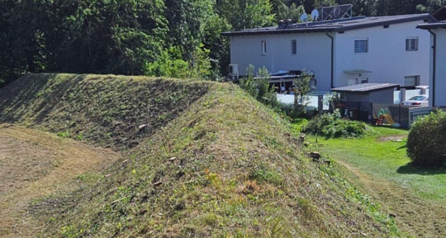 Auf einem grasbewachsenen Hügel steht ein weißes Haus.