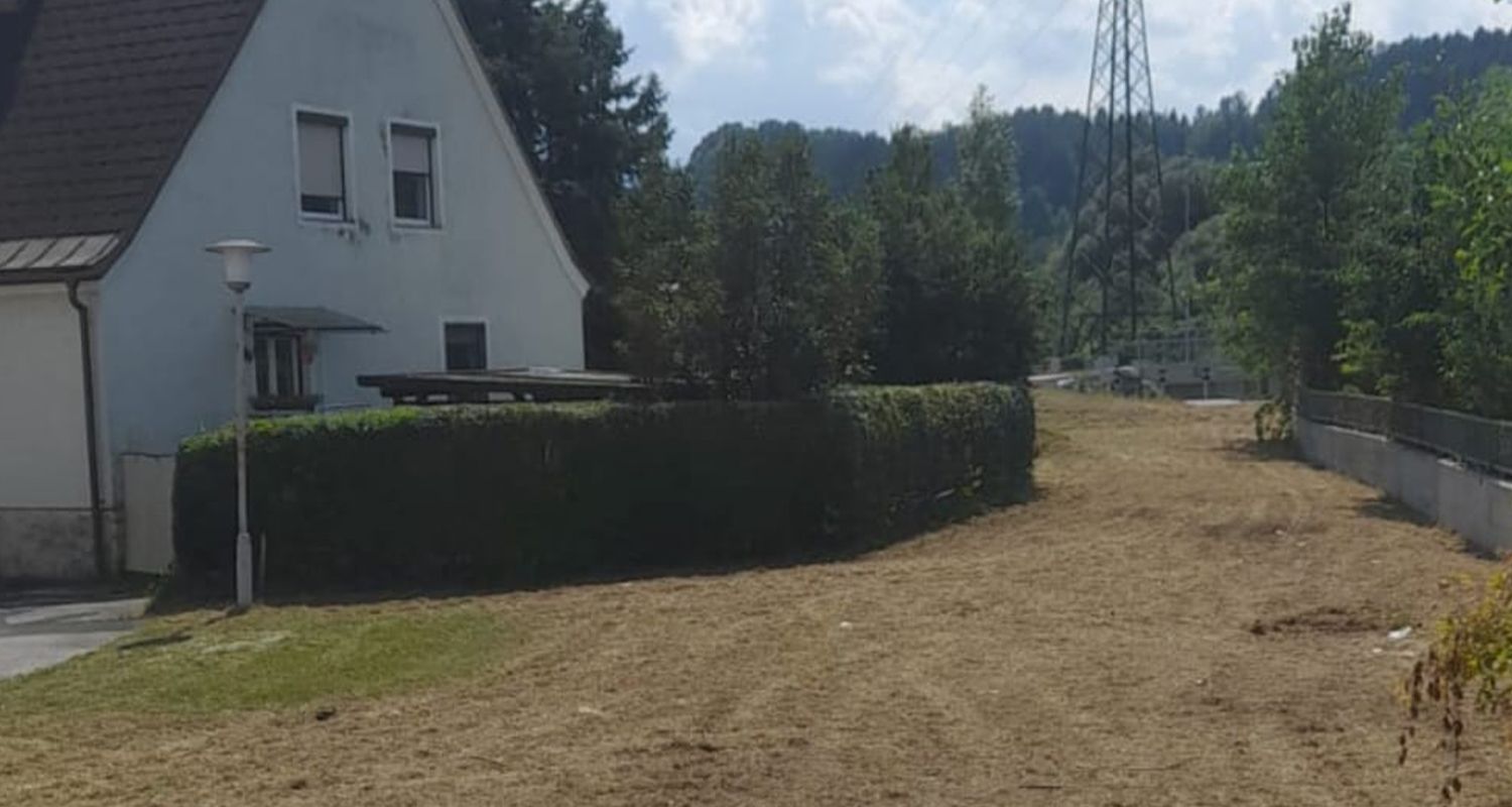 Ein weißes Haus steht neben einem unbegrünten Feld.