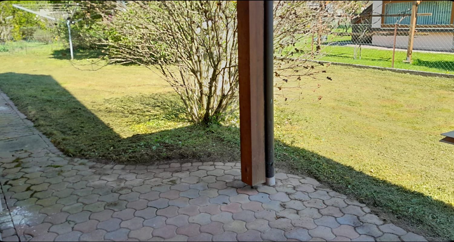 Eine gemauerte Terrasse mit einer hölzernen Pergola mit Blick auf ein üppiges grünes Feld.