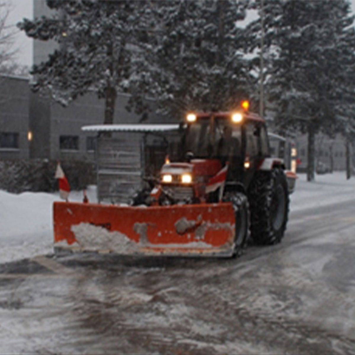Ein Schneepflug fährt eine verschneite Straße entlang