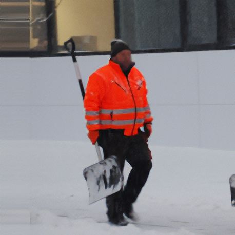 Ein Mann in einer orangefarbenen Jacke trägt eine Schneeschaufel