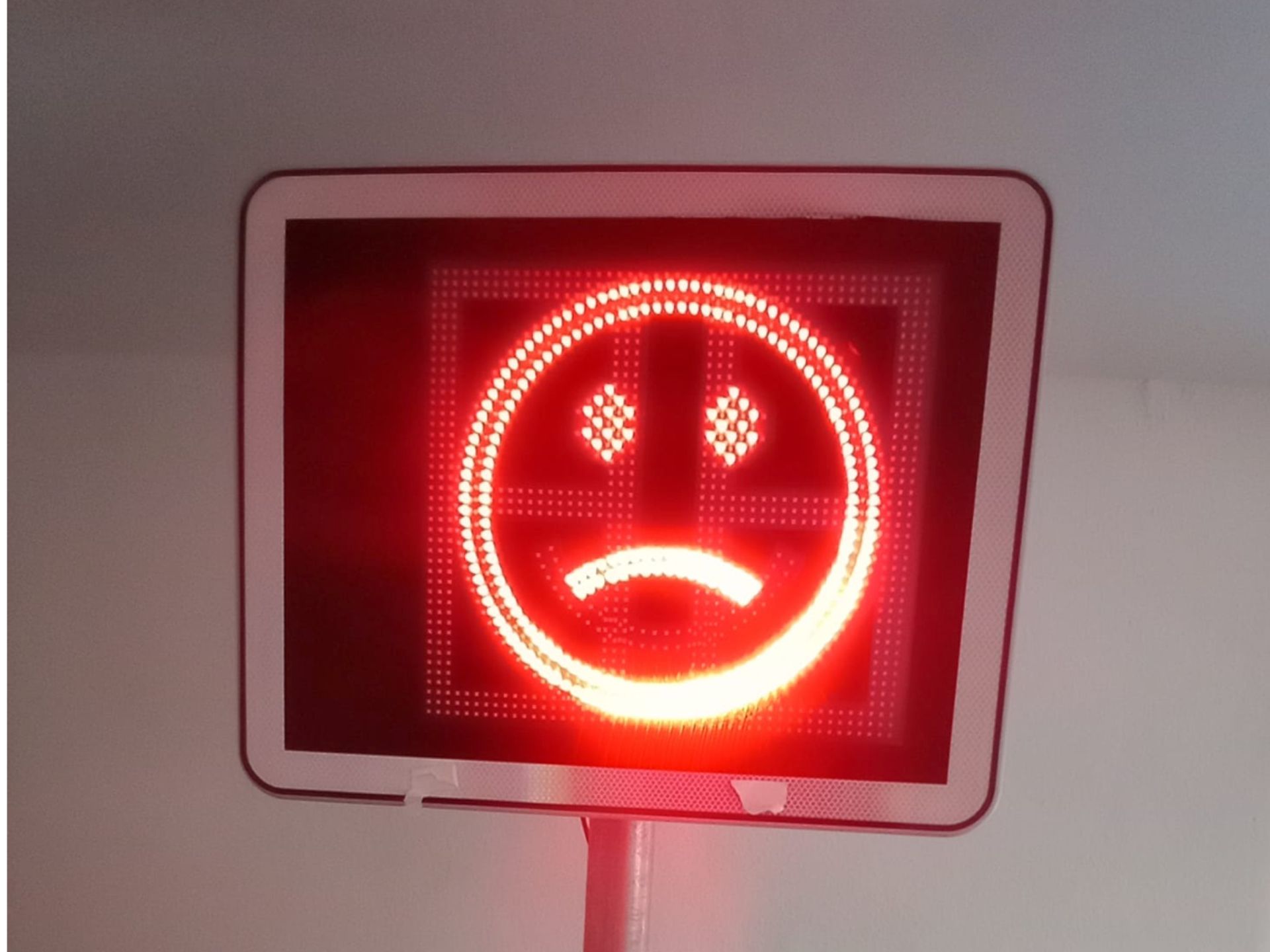 Ein rotes Schild mit einem traurigen Gesicht darauf