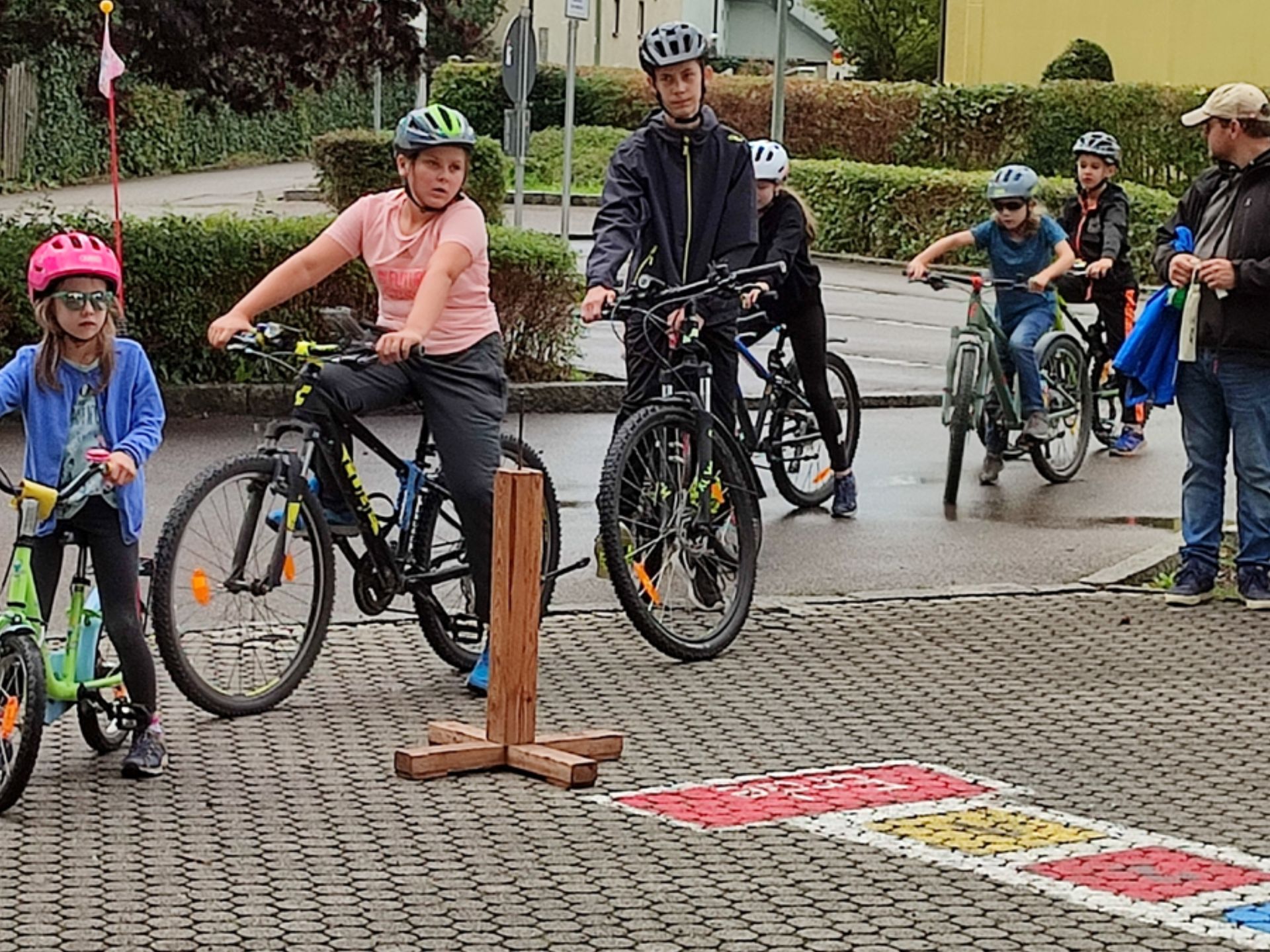 Eine Gruppe Kinder fährt mit dem Fahrrad auf einem Parkplatz.