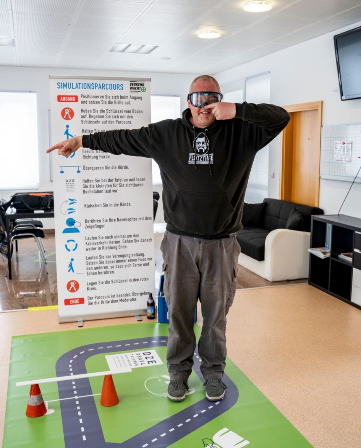 Ein Mann mit Schutzbrille steht vor einem Schild mit der Aufschrift SMLP-Prävention
