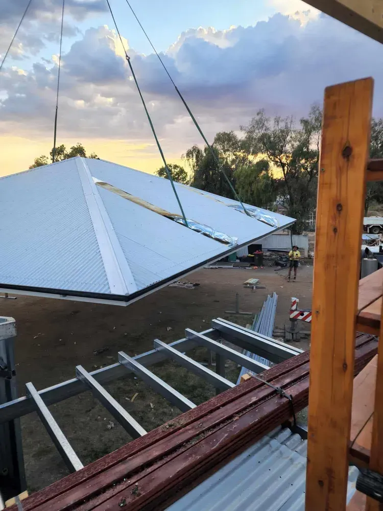 A large piece of metal is being lifted by a crane — Trussted Frames & Trusses In Taminda, NSW