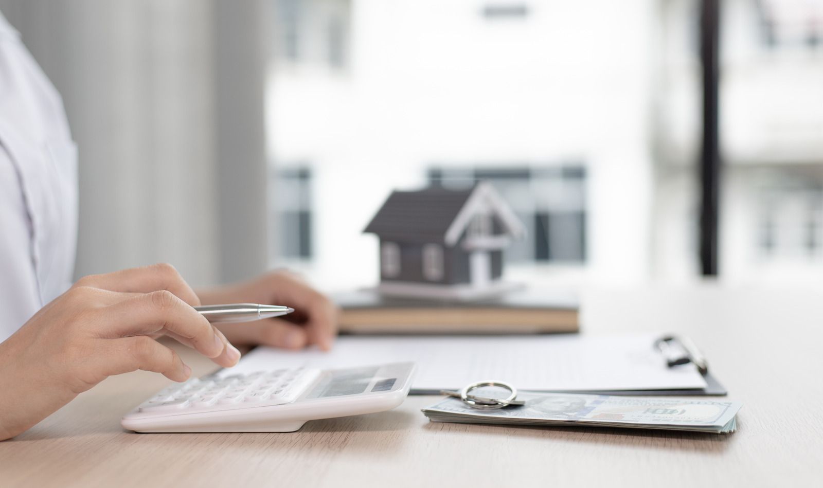 A person is using a calculator to calculate the cost of buying a house.