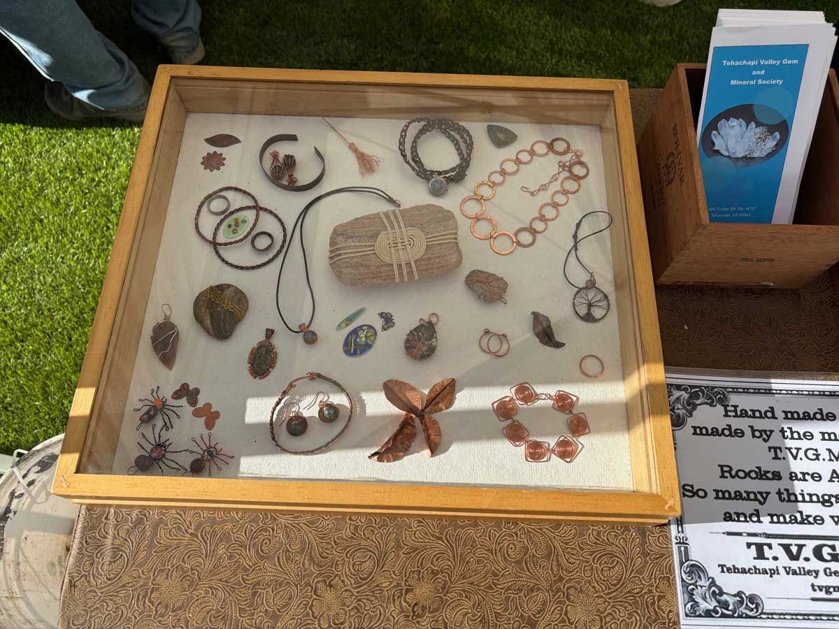 A display case filled with handcrafted jewelry and small decorative items at an outdoor market.