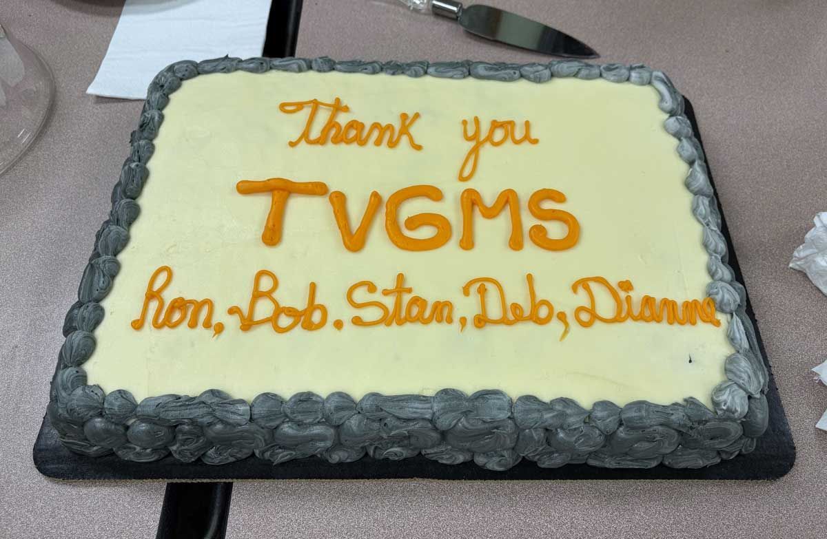 Thank-you cake with orange icing: “TV6MS” and “Ron, Bob, Stan, Bob, Diane” on white frosting.