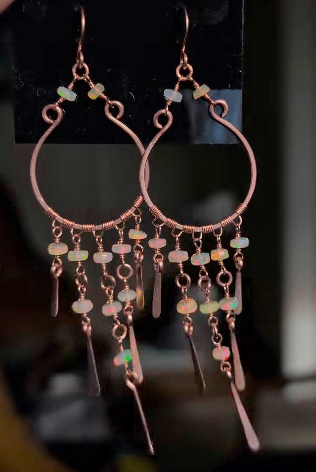 Pair of copper hoop earrings with dangling beads on a dark background
