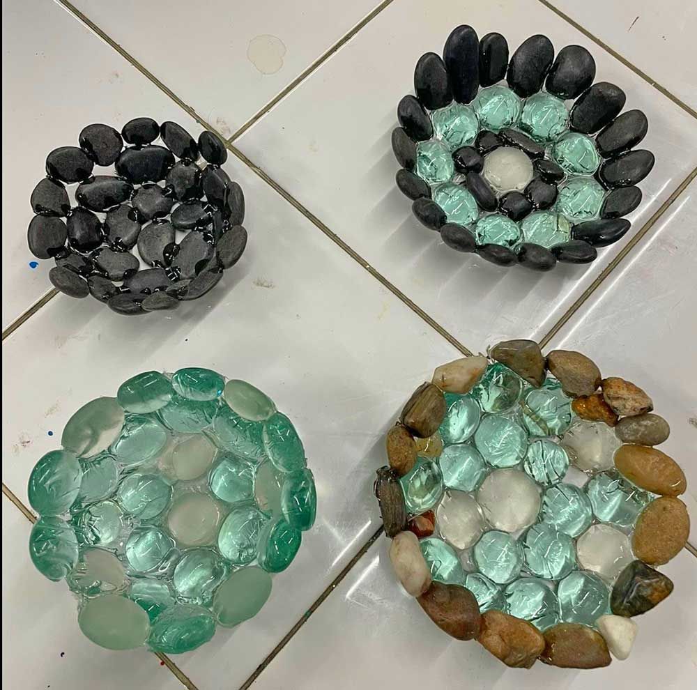 Four circular stone and glass decorative bowls sitting on a tiled surface.