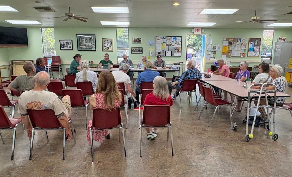 People seated in at the TVGMS community room facing a front table during a group TVGMS meeting or presentation.