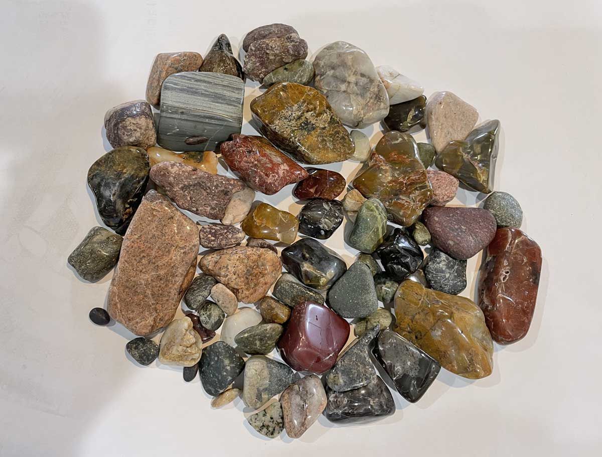 Pile of assorted small multicolored pebbles and rocks on a white background