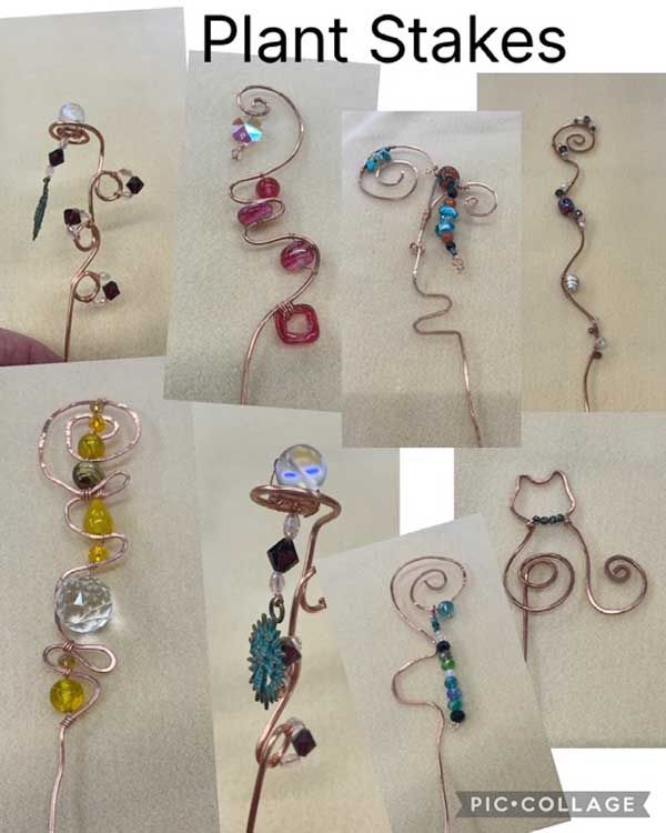 Assorted decorative plant stakes made from wire, beads, and crystals on a beige background