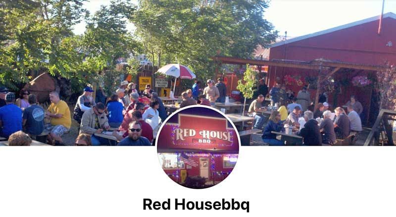 Crowded outdoor patio at Red House BBQ with people gathered under trees and a red building backdrop