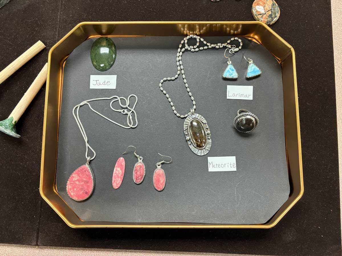 Jewelry display tray with necklaces, earrings, and pendants in silver, turquoise, pink, and black