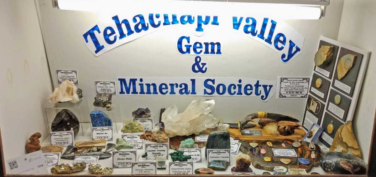 Tehachapi Valley Gem & Mineral Society display table with rocks, minerals, and signs