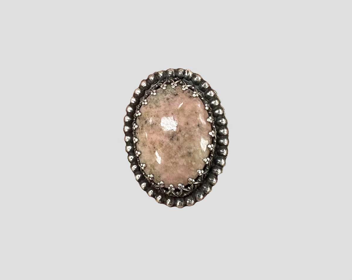 Oval pink gemstone pendant with a dark ornate beaded border