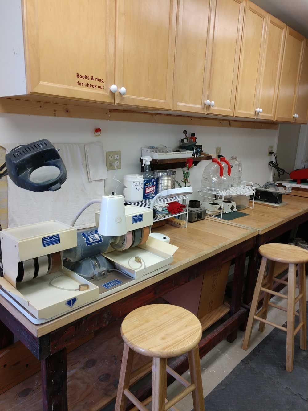 Workbench with lab equipment, cabinets, and stools in a small workshop or classroom lab