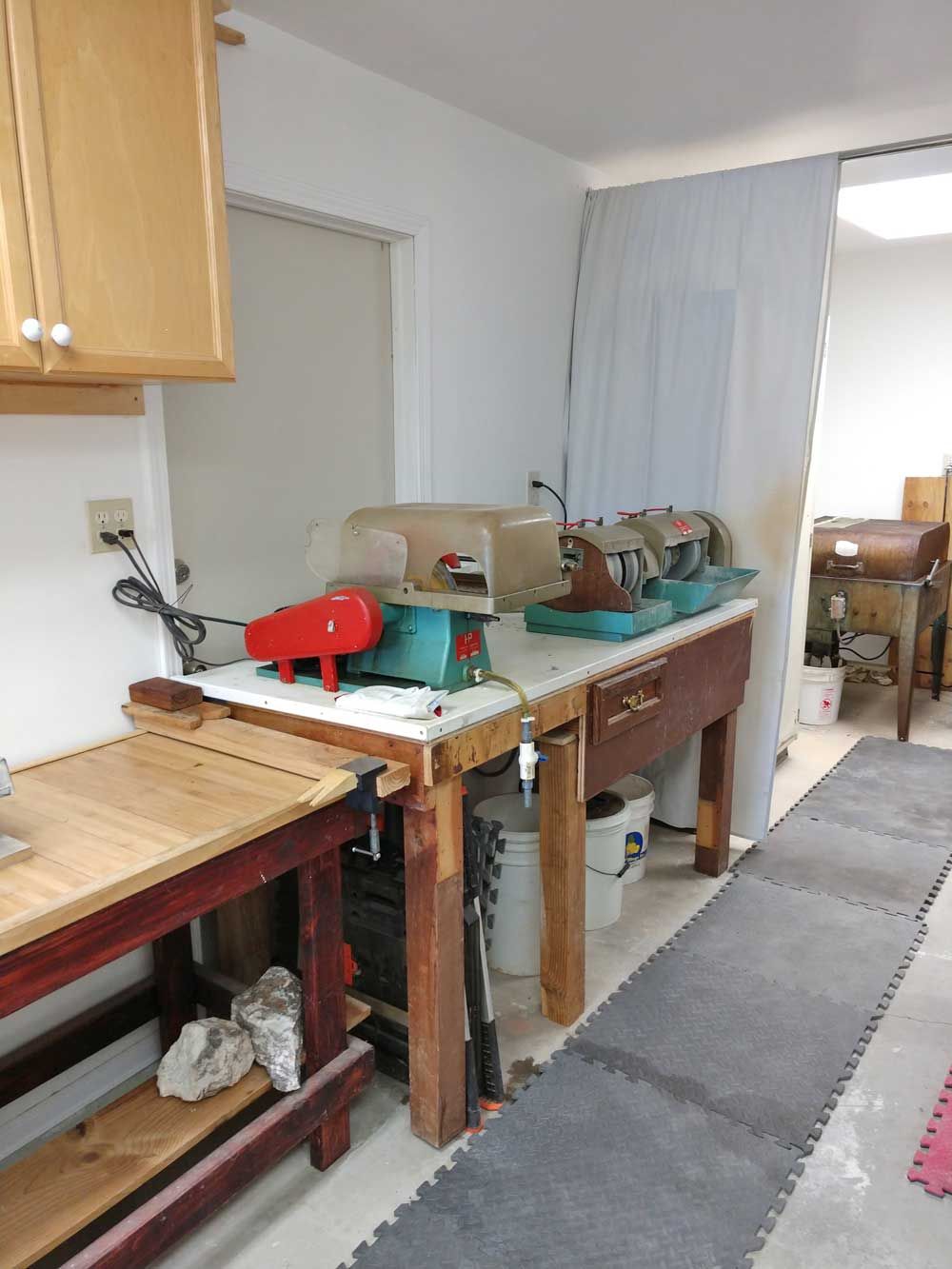Kitchen workshop with a wooden workbench, tools, and a red machine along a narrow room.