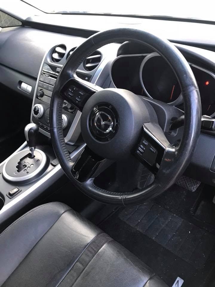 Interior of a right-hand drive Mazda, showing the steering wheel, center console, and front seats