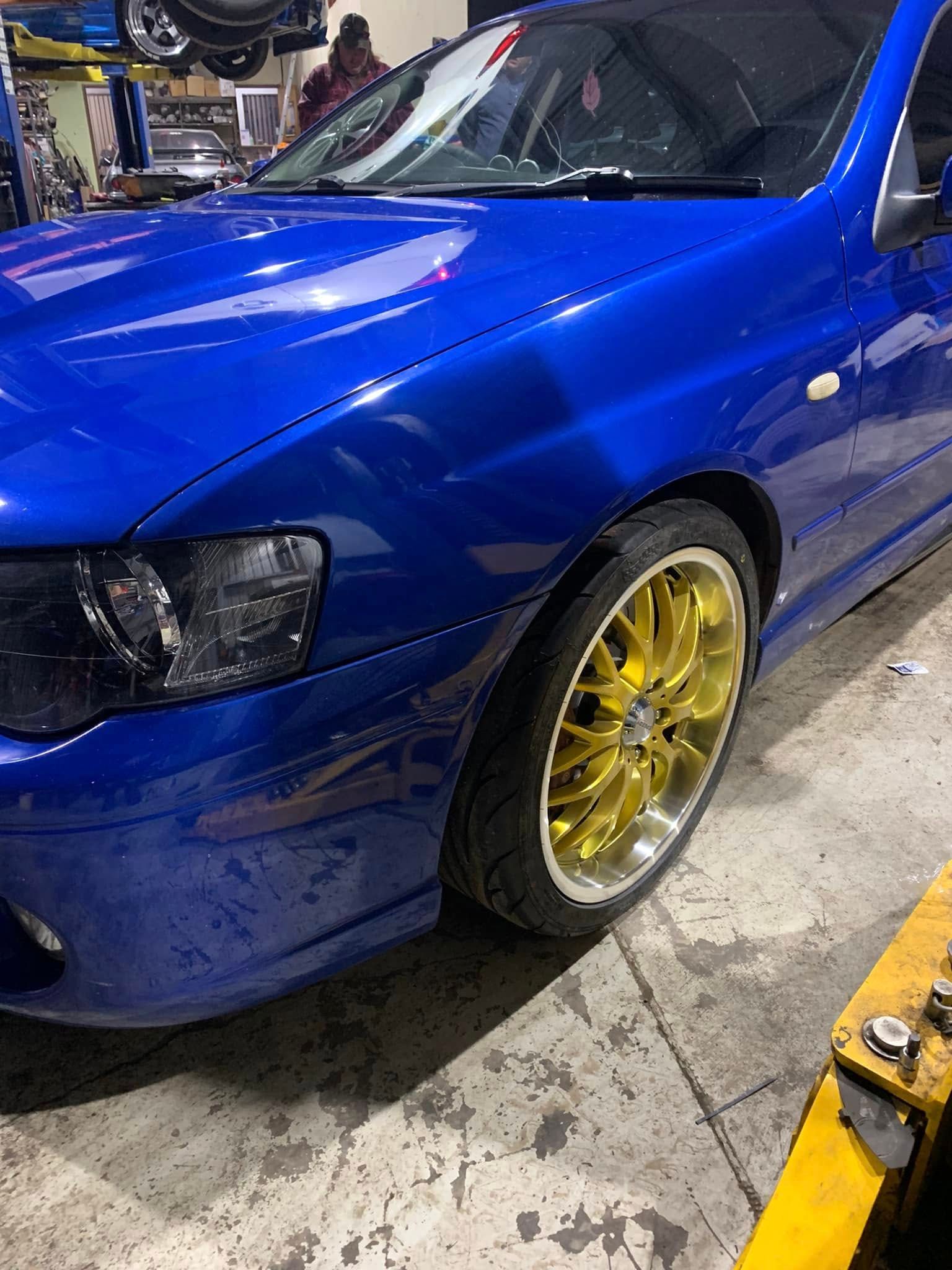 Blue car with gold rims parked in a garage area