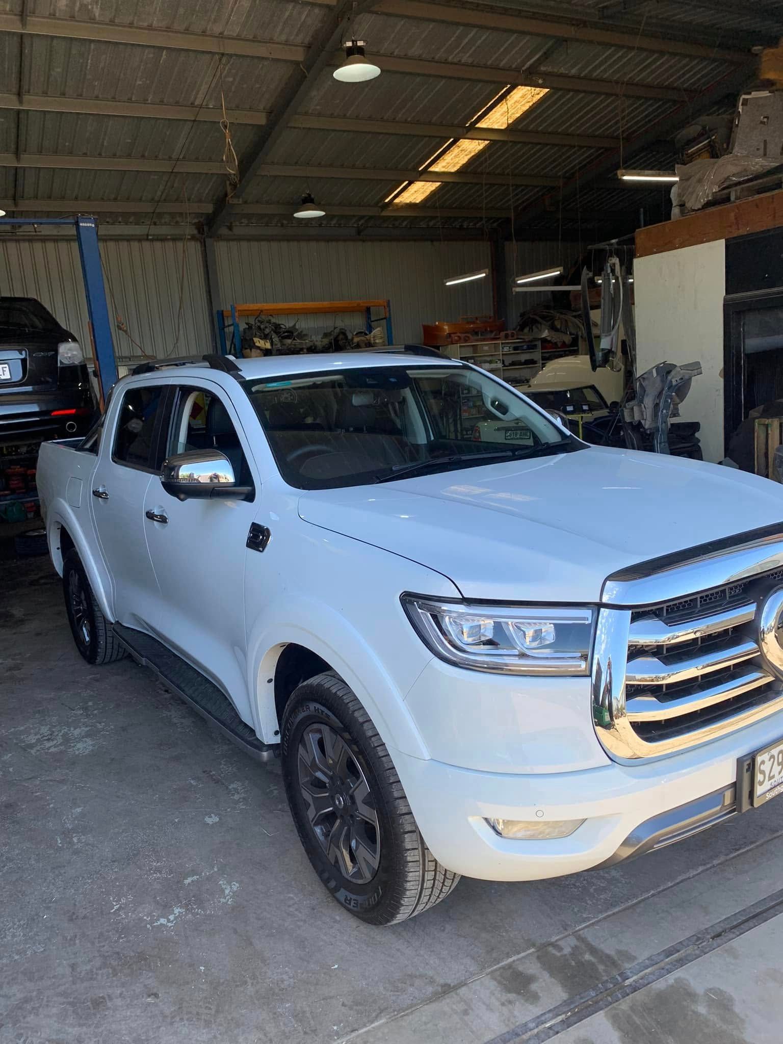 White pickup truck parked inside a garage workshop, front view.