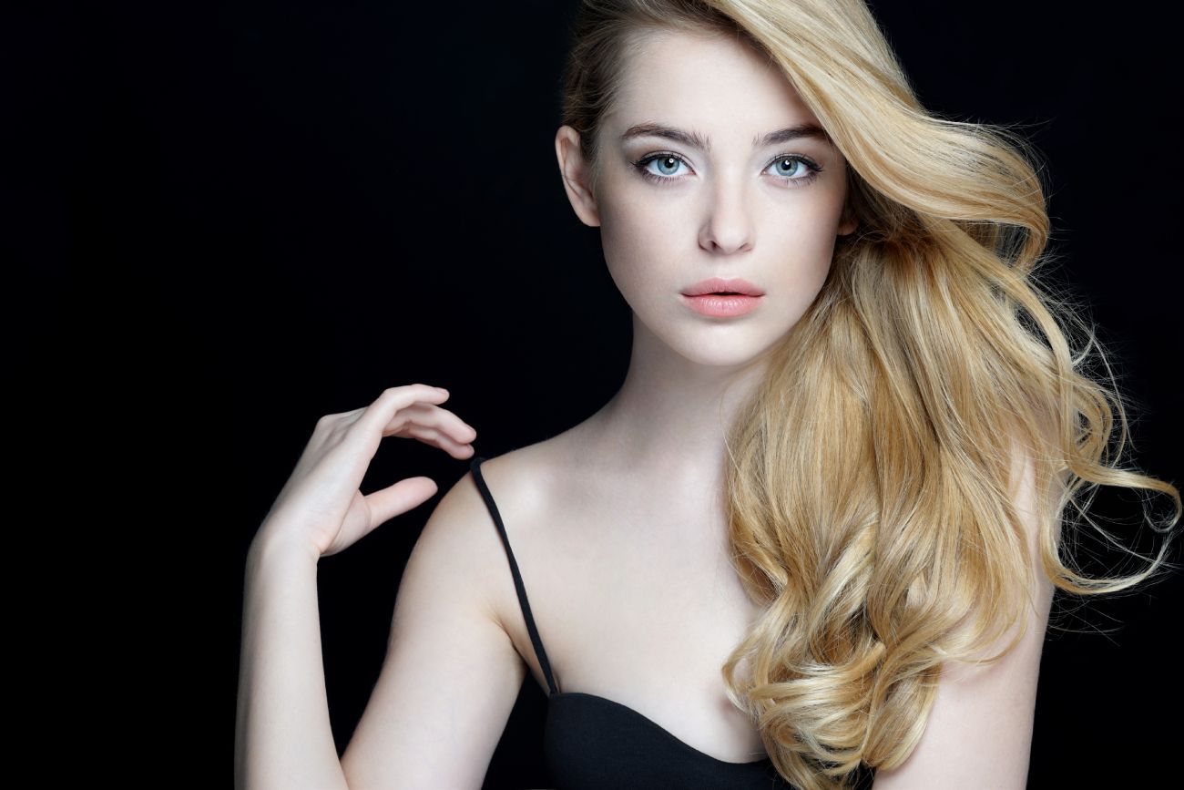 a woman with long blonde hair is wearing a black dress