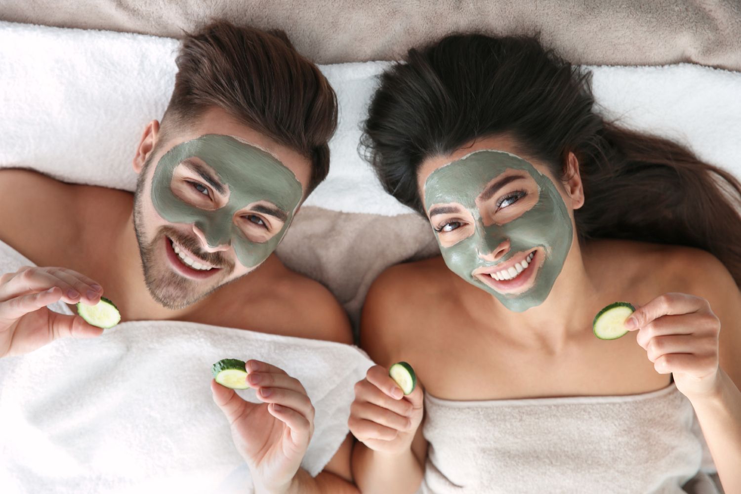a man and a woman are laying on a bed with facial masks on their faces