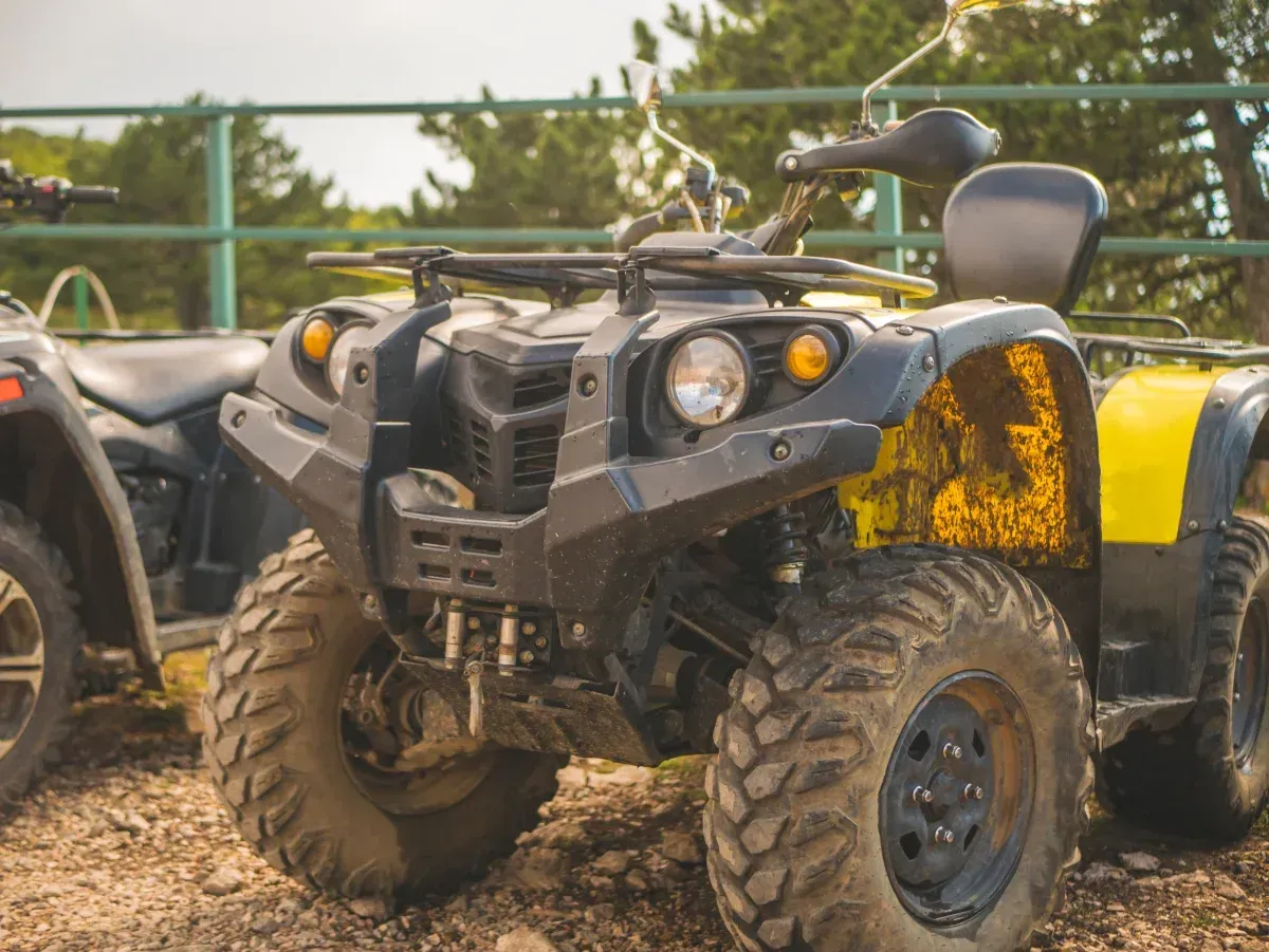 Black and yellow ATV parked outdoors near a green metal fence — Jack Too You Mobile Servicing and Repairs In Sunshine Coast, QLD