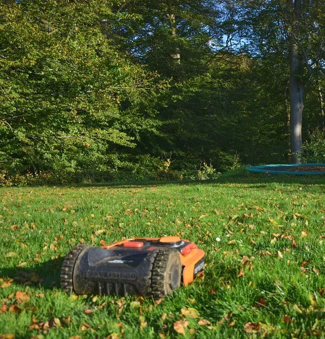Orange and black robotic lawn mower on a green grassy lawn — Jack Too You Mobile Servicing and Repairs In Goomboorian, QLD
