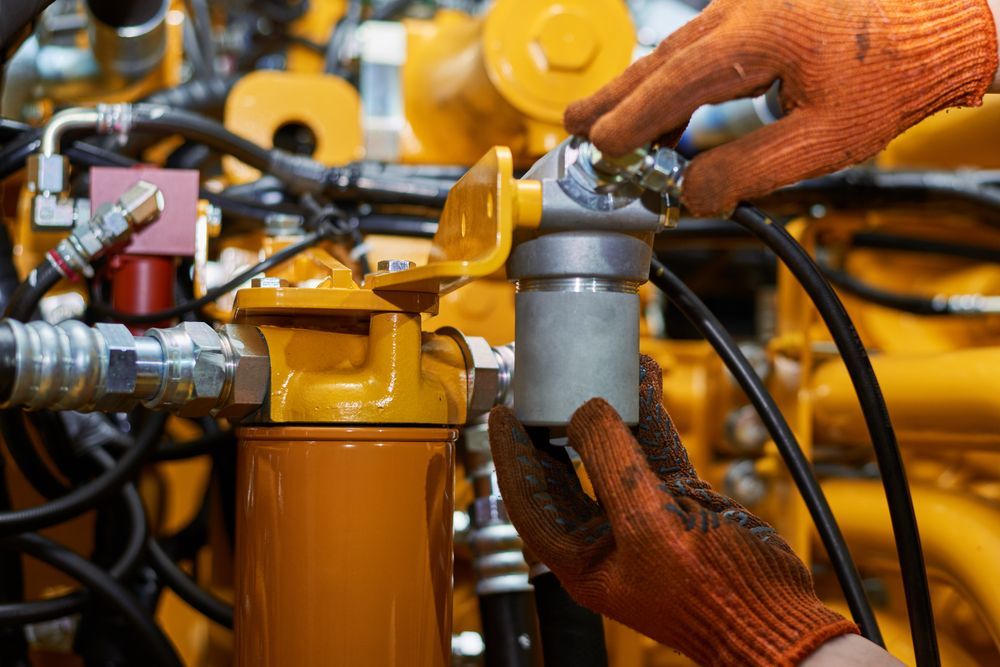 Hands Wearing Orange Gloves Are Working On Yellow Machinery — Jack Too You Mobile Servicing and Repairs In Goomboorian, QLD