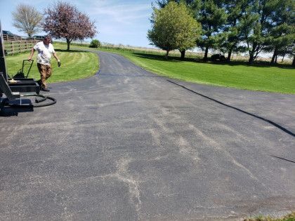 A man is walking down a driveway with a vacuum cleaner.